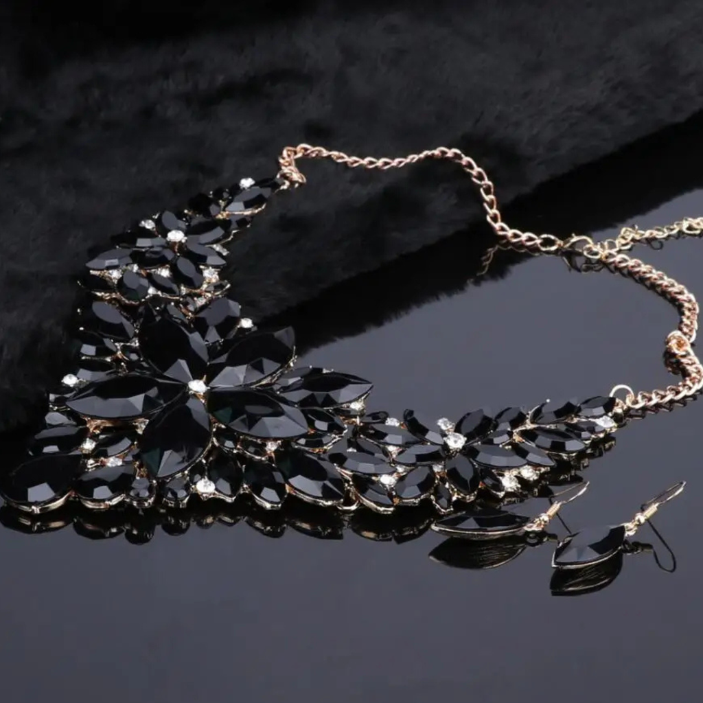 Elegant black crystal bridal jewelry set with floral statement necklace and matching earrings on gold chain, perfect for weddings and formal occasions