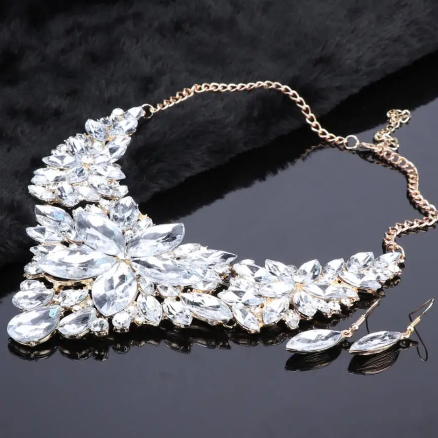 Elegant clear crystal bridal jewelry set with floral statement necklace and matching earrings on gold chain, perfect for weddings and formal occasions