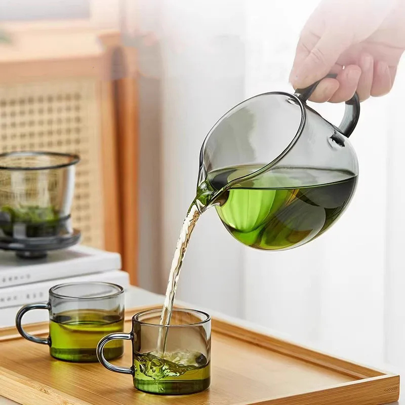 Glass teapot pouring green tea into cups, heat-resistant borosilicate loose leaf tea maker with modern tea set