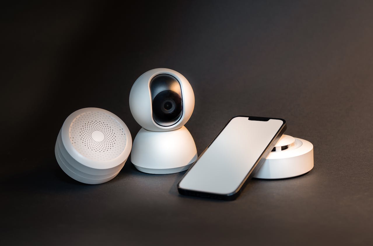 Modern white smart home security camera system with a wireless speaker and smartphone integration on a dark background for Havenicstore's premium electronics collection.