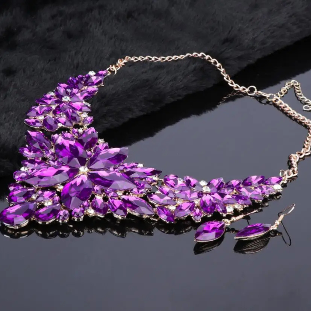 Elegant purple crystal bridal jewelry set with floral statement necklace and matching earrings on gold chain, perfect for weddings and formal occasions