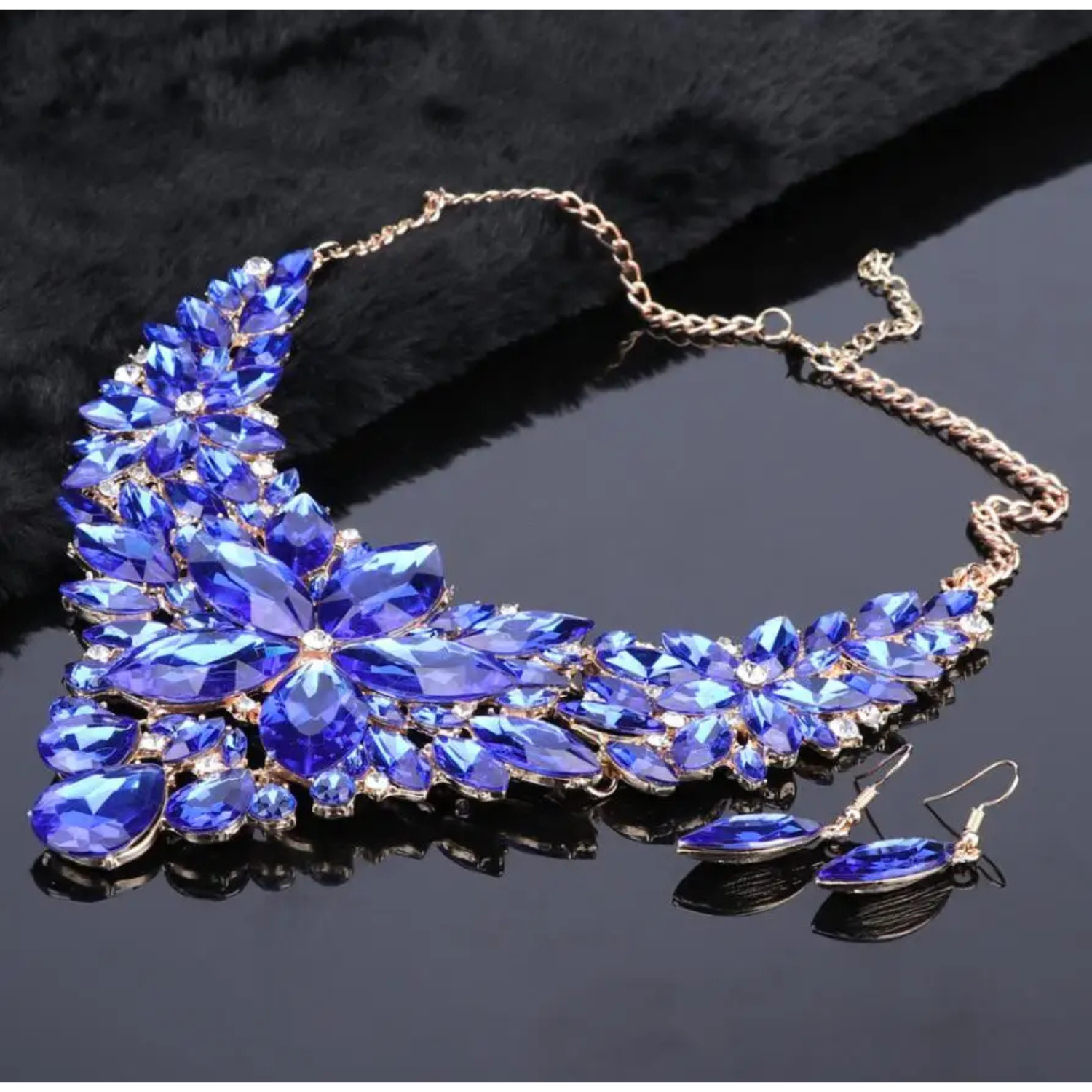 Elegant royal blue crystal bridal jewelry set with floral statement necklace and matching earrings on gold chain, perfect for weddings and formal occasions